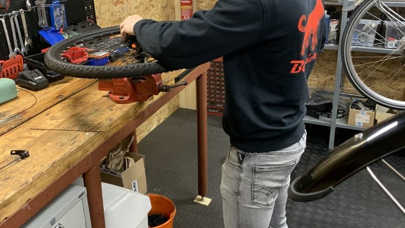 Monteur voert onderhoud en reparaties uit aan elektrische fatbike wiel in werkplaats – gespecialiseerd in e-bike service en herstel.