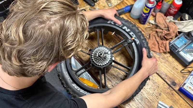 Monteur plaatst buitenband op achterwiel van elektrische fatbike – onderhoudswerkplaats Bouvier Bikes.