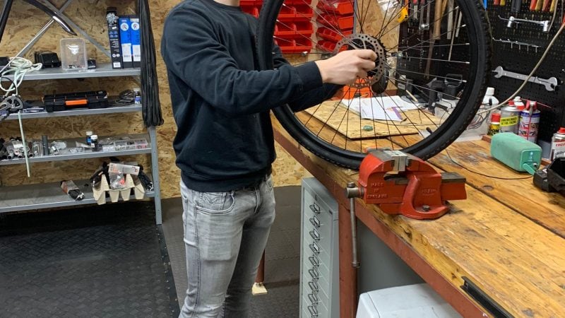 Monteur voert wielinspectie uit op werkbank – vakkundig onderhoud aan elektrische fietsen en fatbikes.