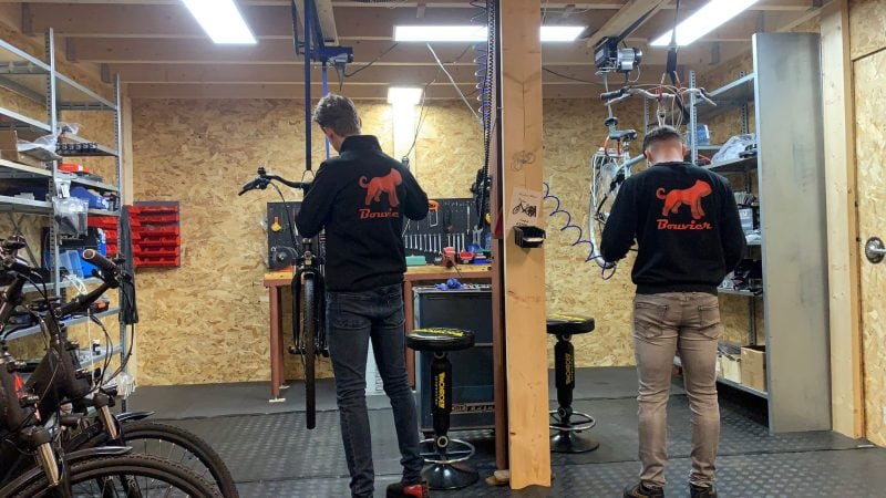 Twee monteurs aan het werk in een professionele e-bike werkplaats – onderhoud en reparatie van elektrische fietsen.