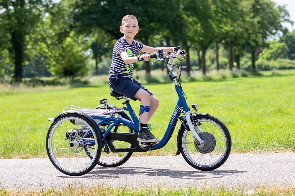 Kind op driewielfiets met stabiele zithouding en trapondersteuning op fietspad
